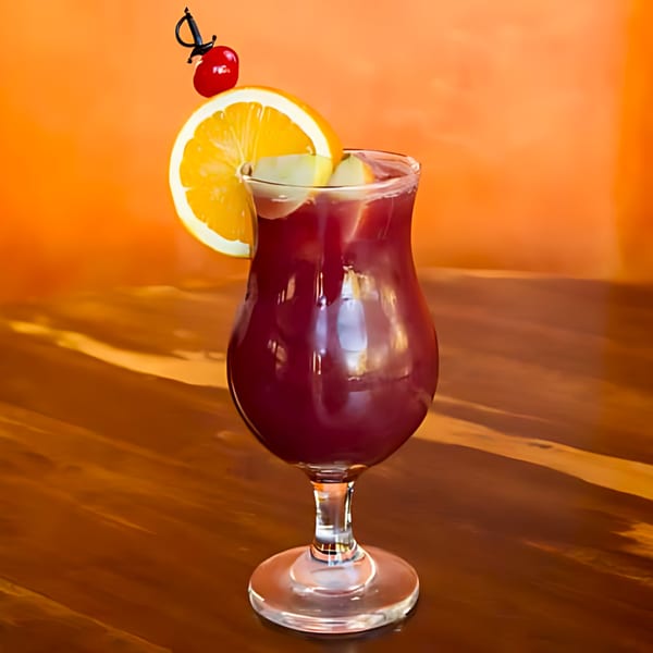 A glass of red sangria with orange slices and cherries on a wooden table.