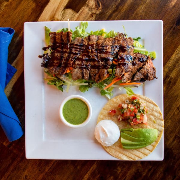 Sonrisa Grill's carne asada with a side of green salsa, sour cream, avocado, and pico de gallo.
