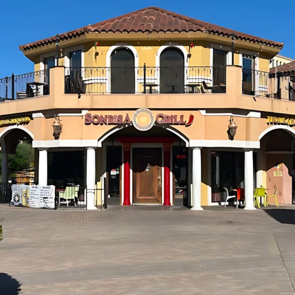 Sonrisa Grill, a two-story Mexican restaurant with a red tile roof and outdoor balcony seating.